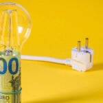 Bombilla, billete y enchufe representando el ahorro de energía y cómo reducir la factura de electricidad de manera eficiente.
